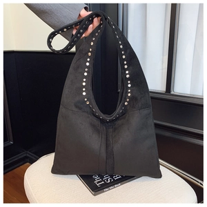 Détail d'un sac hobo en daim noir vintage avec des rivets argentés sur la large bandoulière