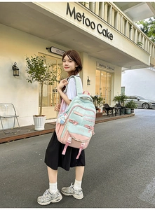 Outdoor lifestyle shot of a mint green and pink student backpack with bow and bunny charm