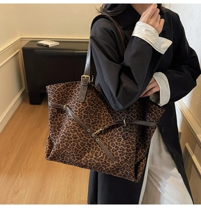 Detail of leopard print suede tote bag featuring brown leather straps and gold buckle