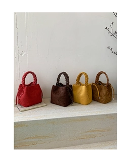 Detail of four colorful suede bucket bags featuring braided handles and drawstring closures