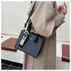Détail du sac à bandoulière en cuir noir avec logo et ruban imprimé élégant