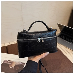 Detailed view of crocodile embossed leather handbag with silver ball charm zippers