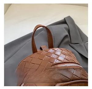 Dettaglio di uno zaino in pelle marrone intrecciata con manico superiore e zip in metallo