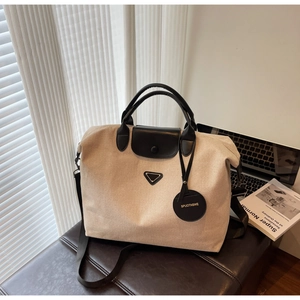 Detailed view of canvas tote bag with black leather handles and iconic triangle logo