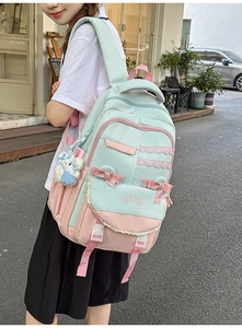 Detail of mint green and pink school backpack with lace edges and plush bear charm