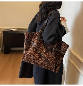 Detail of large leopard print tote bag with dark brown straps and metal buckle accents