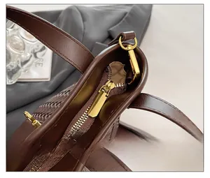 Dettaglio della cerniera dorata e della trama in pelle intrecciata marrone scuro della borsa