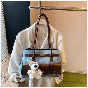 Detail of blue denim tote bag with brown leather trim and cute plush puppy charm