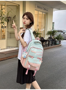 Detail showing mint green and pink school backpack with bow decoration and bear charm