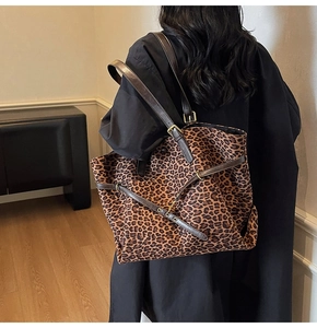 Detail of leopard print tote bag with brown leather straps and gold buckle on a model
