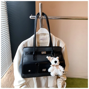 Close-up of black tote bag with metallic twist-lock and cute bear plush charm