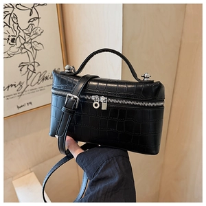 Detail of black crocodile pattern crossbody bag featuring silver double zipper closure