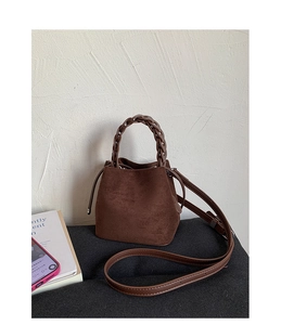Detail of vintage brown suede bucket bag featuring a woven leather handle and side texture