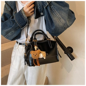 Detail view of black vintage boston bag with white stitching and cute bear charm accessory