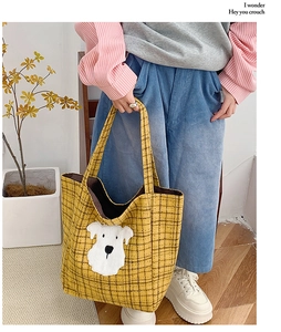 Detailed view of yellow plaid tote bag with cute white puppy embroidery on a model