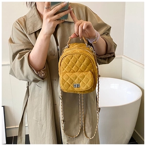 Detail of yellow quilted backpack featuring chain straps and metallic turn-lock