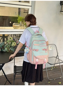 Detail of mint green and pink school backpack with lace, bow, and embroidery
