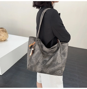 Detail of vintage oversized faux leather tote bag with wooden bead charm on shoulder