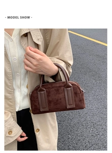 Detail of suede textured coffee brown handbag with leather handle and top zipper closure