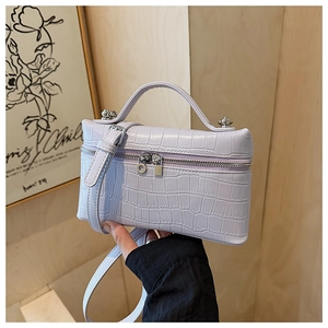 Detail view of light purple crocodile pattern handbag with silver hardware and top handle