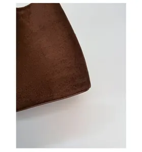 Close-up of the dark brown suede texture and stitching on the minimalist bucket bag corner