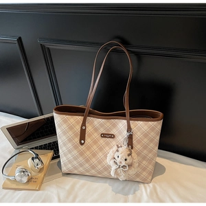 Dettaglio borsa tote a scacchi beige con cinturini in pelle marrone e ciondolo a coniglio