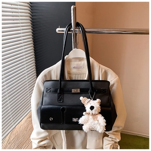 Detail of black tote bag featuring double front pockets and white plush bear charm