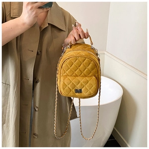 Close-up of ginger quilted mini backpack with velvet texture and silver chain strap