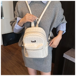 Dettaglio della trama in pelle intrecciata e delle tasche con cerniera dello zaino beige