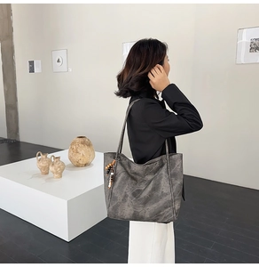 Large dark grey washed tote bag for women shown as a shoulder bag in minimalist art studio