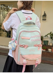Outdoor view of a mint green and pink school backpack with bow and lace details