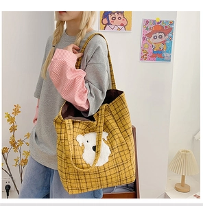Detail of yellow plaid tote bag featuring a large white puppy patch and long shoulder strap