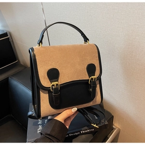 Detail view of vintage brown suede backpack with black leather accents and metal buckles