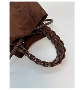 Detailed view of woven ring handle on dark brown suede handbag with high quality texture