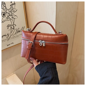 Detail of brown crocodile pattern small box bag with silver zipper and sturdy top handle