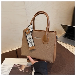 Détail du sac cabas marron avec sangle logo tendance et poignées en similicuir