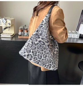 Detail of plush leopard print tote bag with black leather straps in cafe setting
