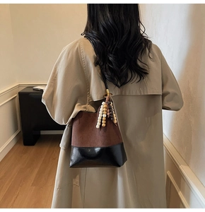 Détail du sac seau en daim mat et cuir avec pendentif décoratif en perles colorées
