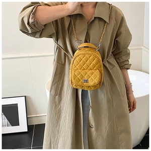 Detail of yellow quilted mini backpack with silver twist lock and chain strap