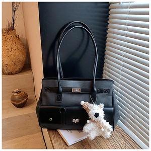 Detail of grey canvas tote bag with black leather pockets and white plush bear pendant