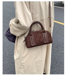 Detail of dark brown suede bowling bag styled with a beige trench coat in a city street
