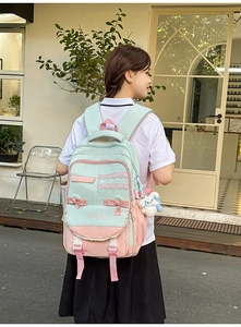 Detail of mint green and pink school backpack with bow and plush bunny pendant