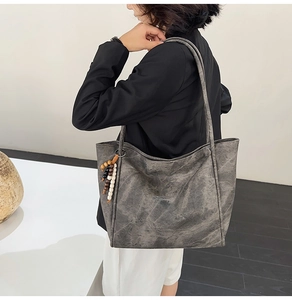 Detail view of large grey hobo bag with vintage texture and wooden bead tassel