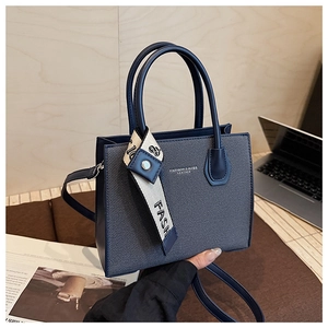 Détail d'un sac bandoulière bleu texturé avec ruban décoratif sur un bureau en bois