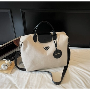 Detail of canvas travel tote bag with black faux leather handles and adjustable shoulder strap