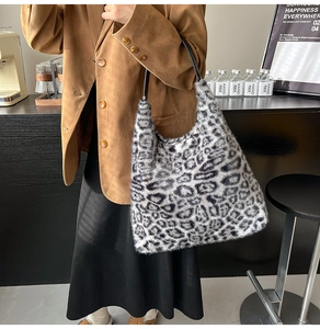 Detail of plush leopard print tote bag with black leather handle in lifestyle setting