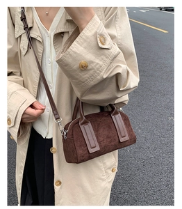Model wearing dark brown suede bowling bag with adjustable strap and silver hardware