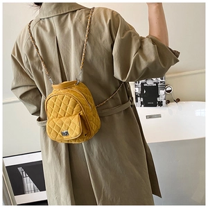 Detail of yellow quilted mini backpack with silver metal chain straps and twist lock closure