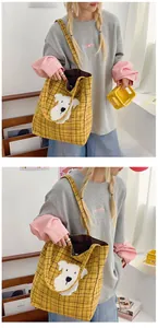 Detail view of yellow plaid tote bag with cute white puppy plush applique and checkered strap