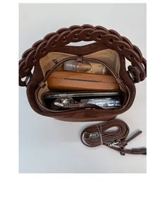 Vertical view showing spacious interior of the brown suede bucket bag with daily items